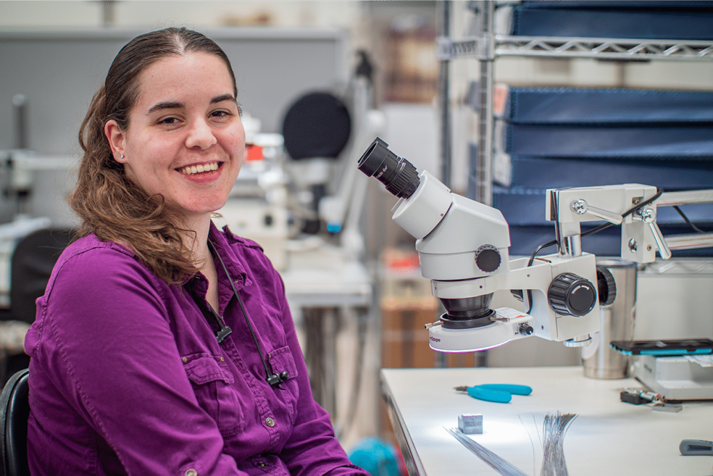 Woman in front of microscope at Motion Dynamics Corporation
