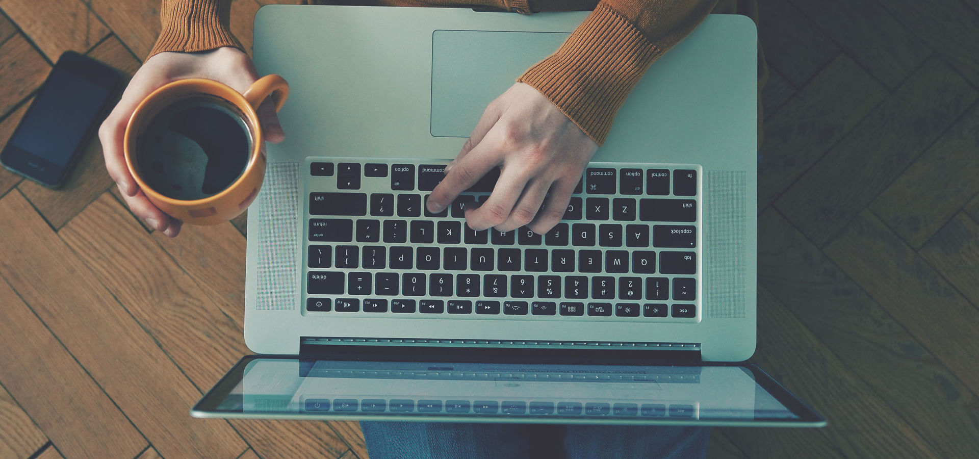 Laptop and coffee cup in girls hands