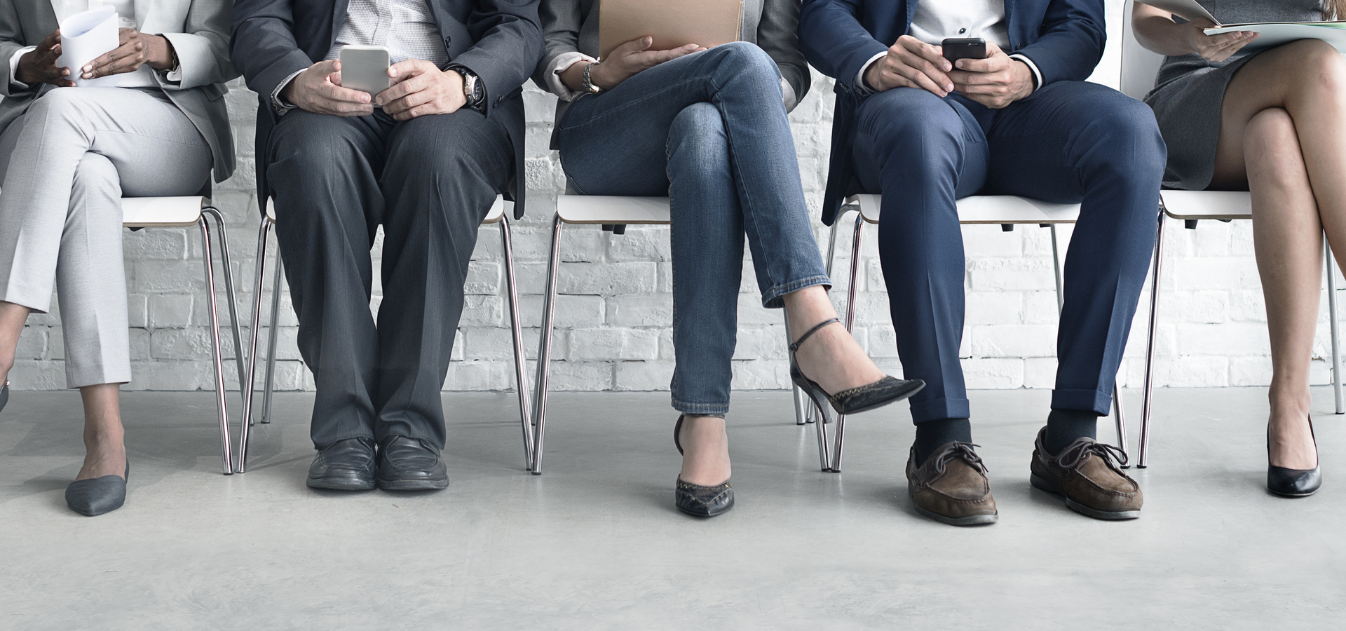 Business people sitting in chairs with electronic devices in their hands
