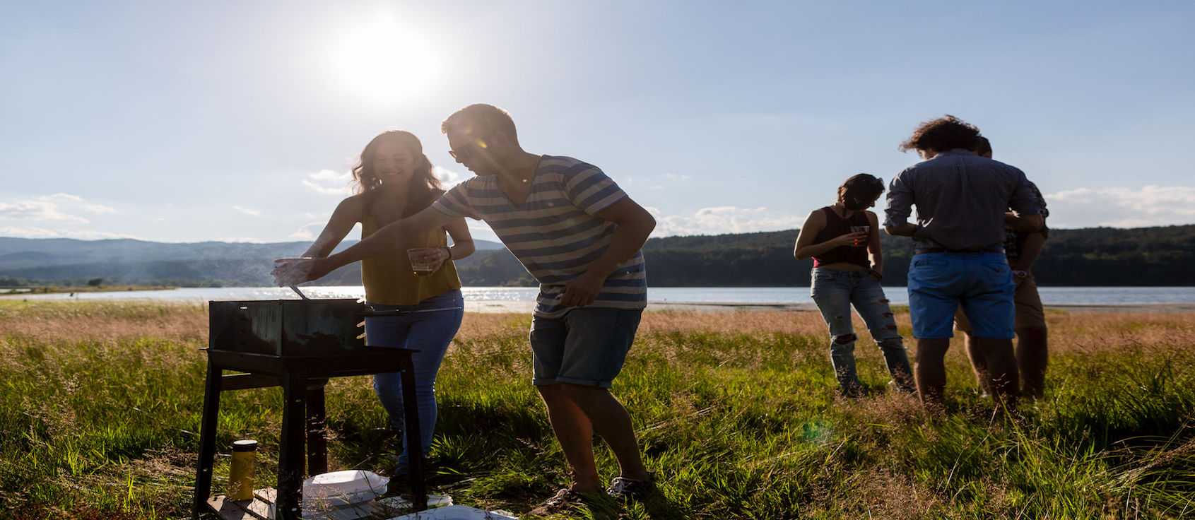 People making barbecue at a lakeside meadow