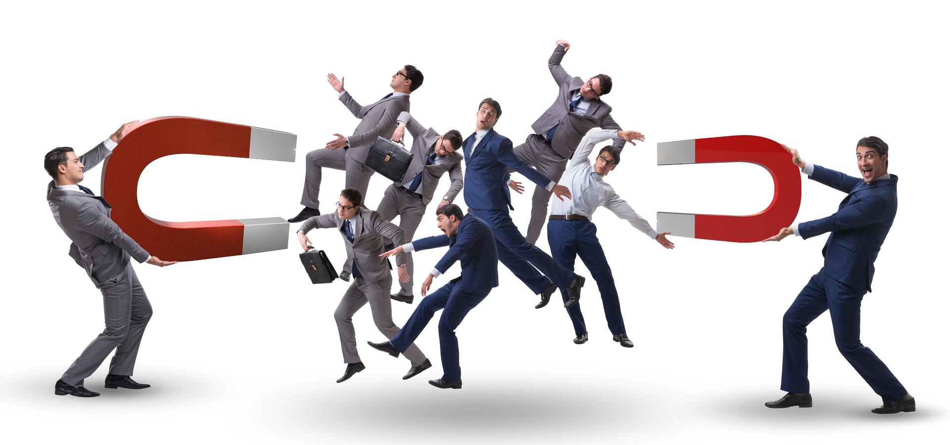 Two men holding big u-shaped magnets with a group of businessmen in the middle