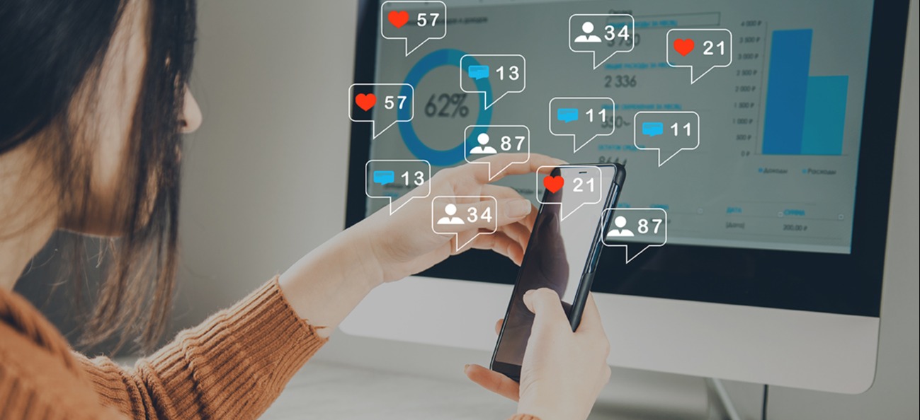 Woman with smartphone in front of computer screen