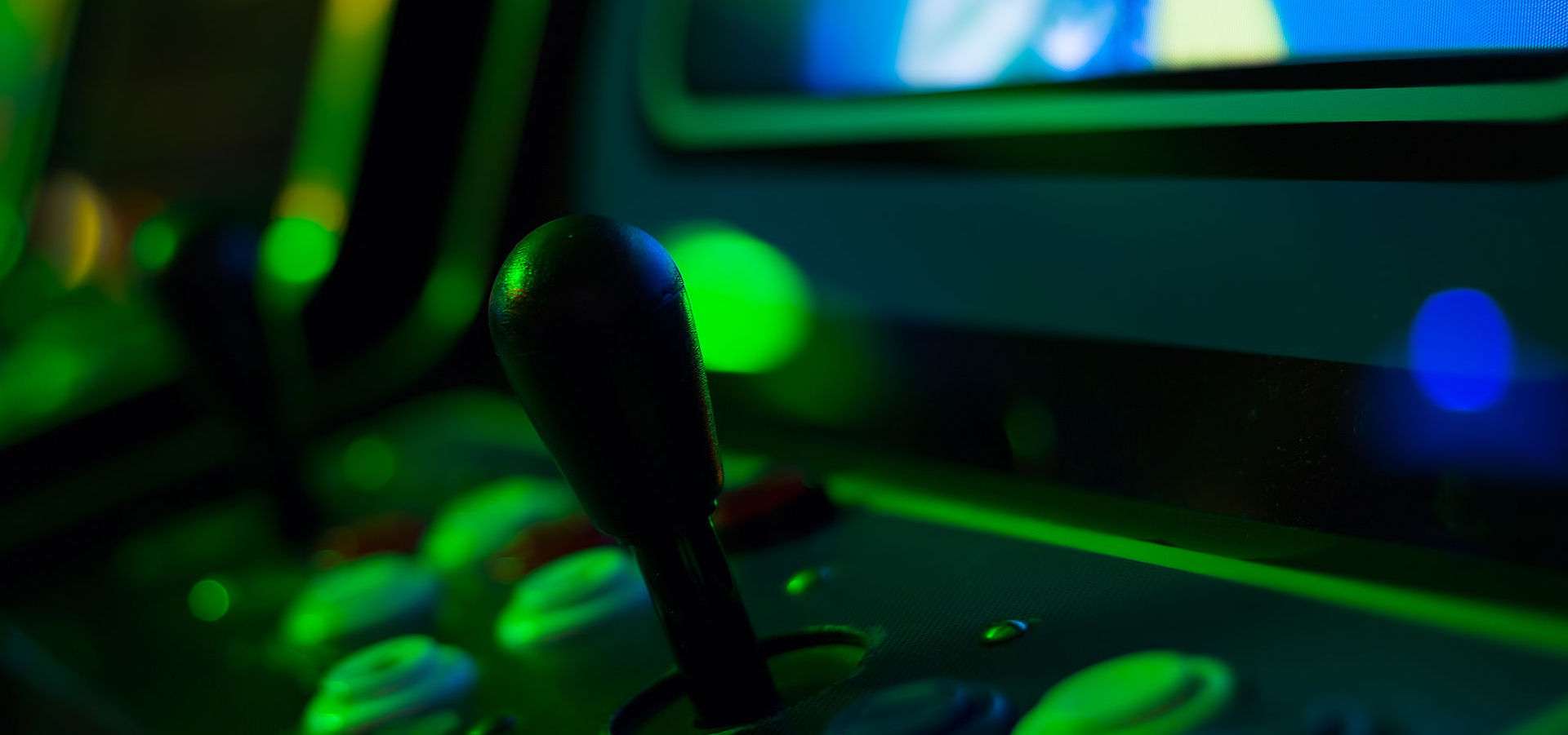 Black joystick and green buttons on an old arcade game