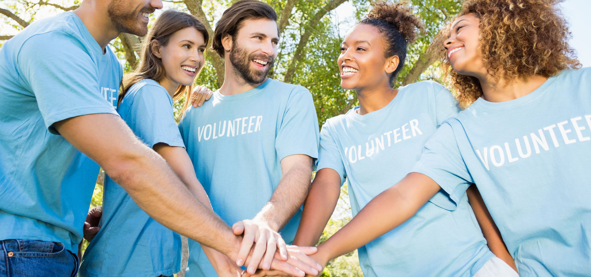 Group of volunteers forming hands stack in park