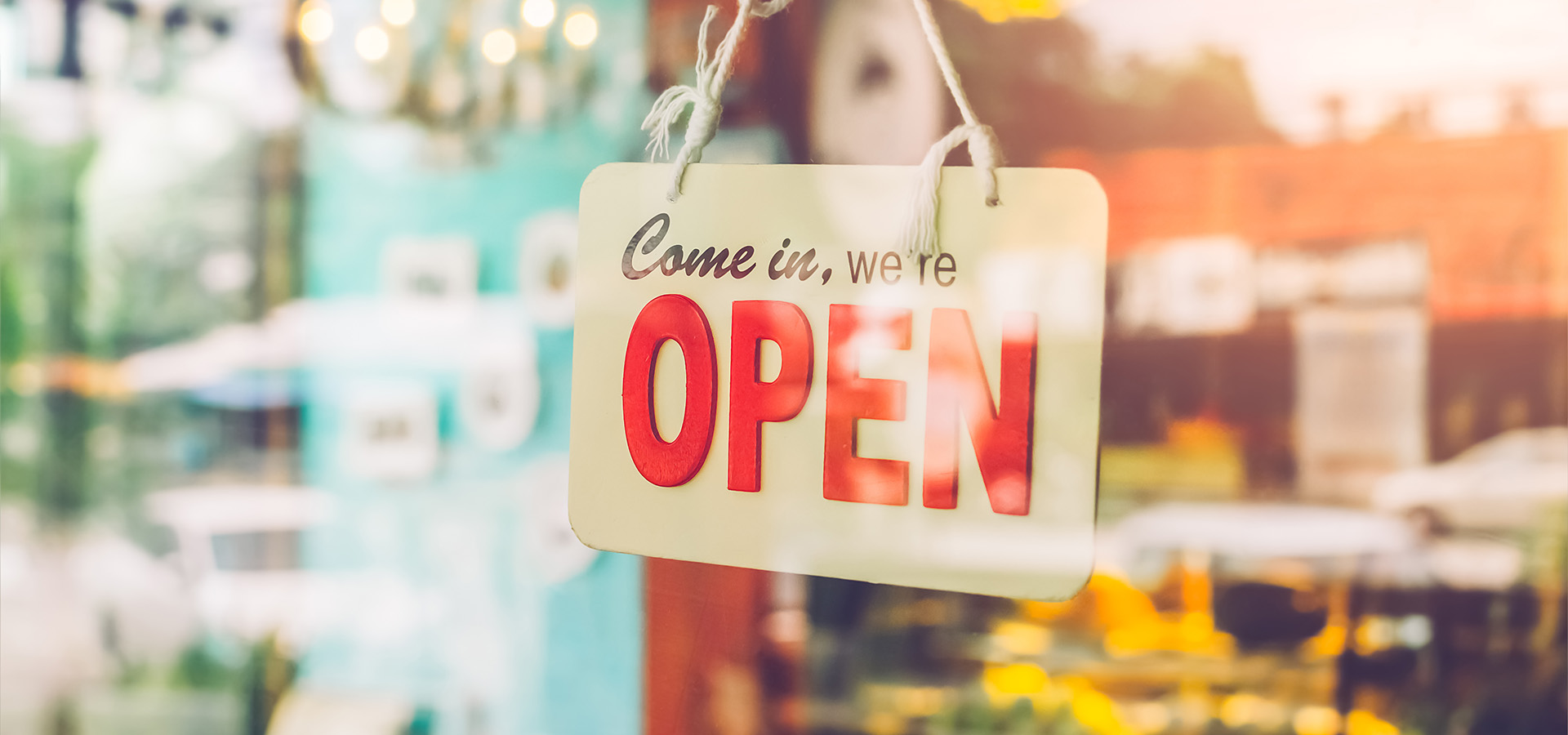 Open sign broad through the glass of door in cafe.