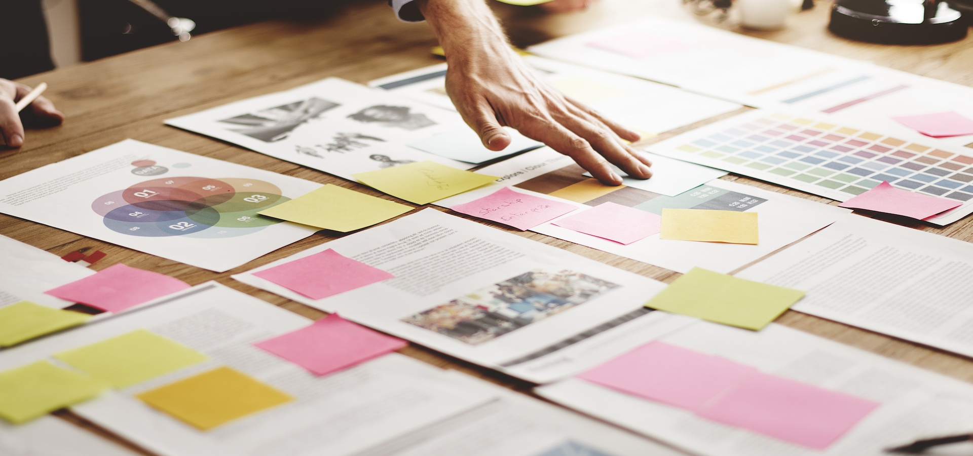 Hand touching papers and sticky notes on table
