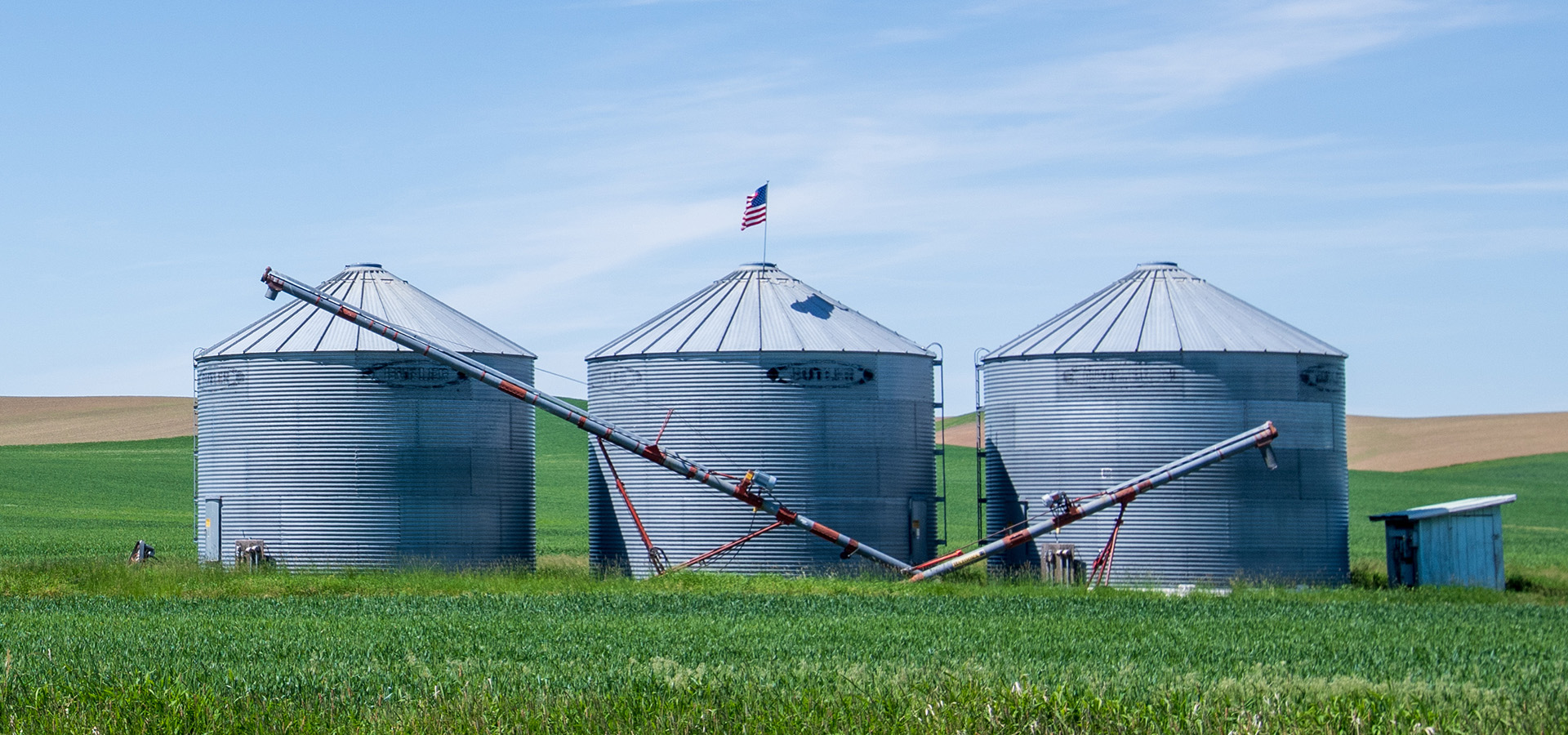 Three grey silos in field