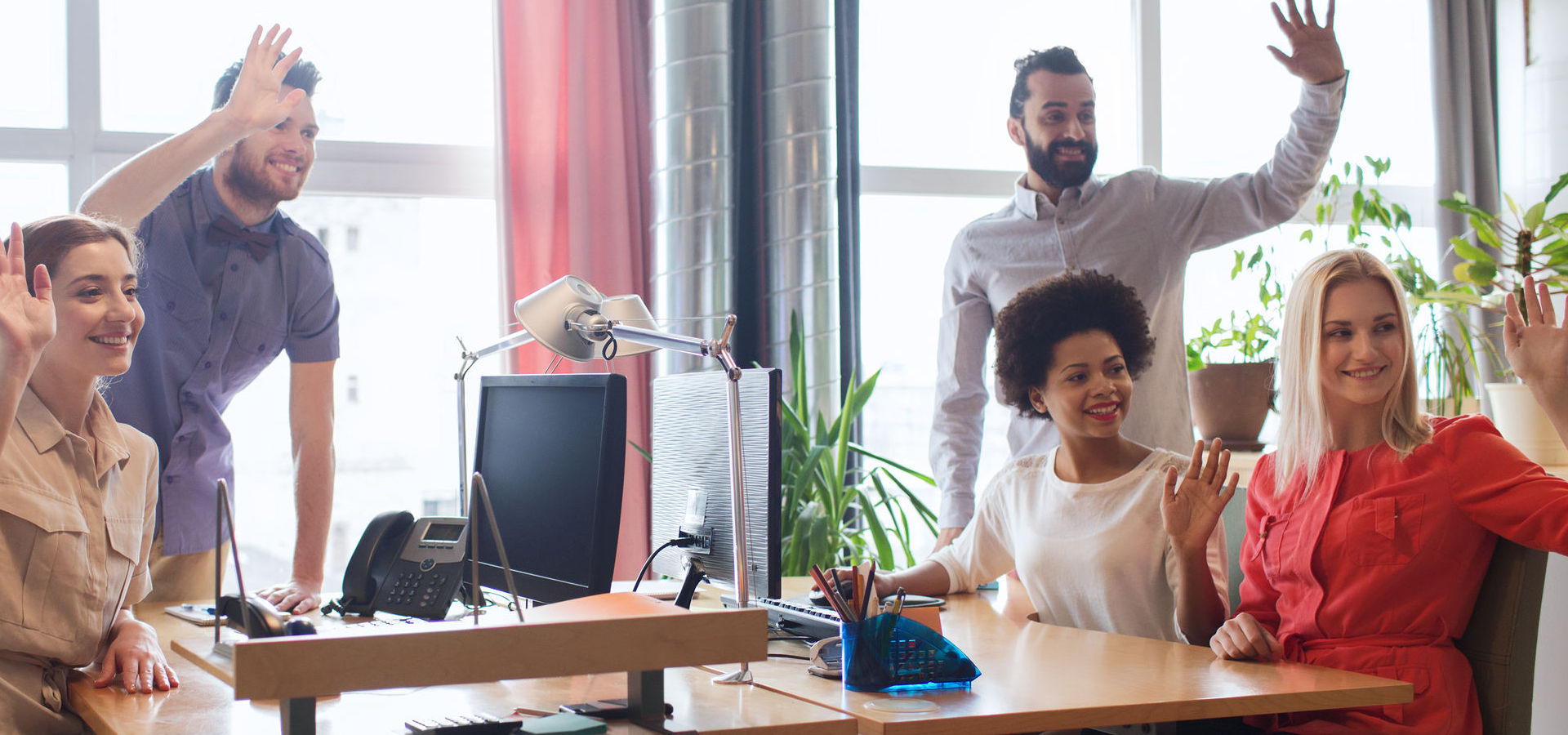 Happy creative team waving hands in office