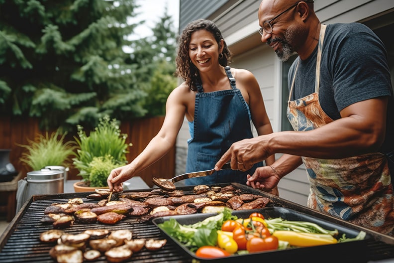 Two older adults grilling outside.